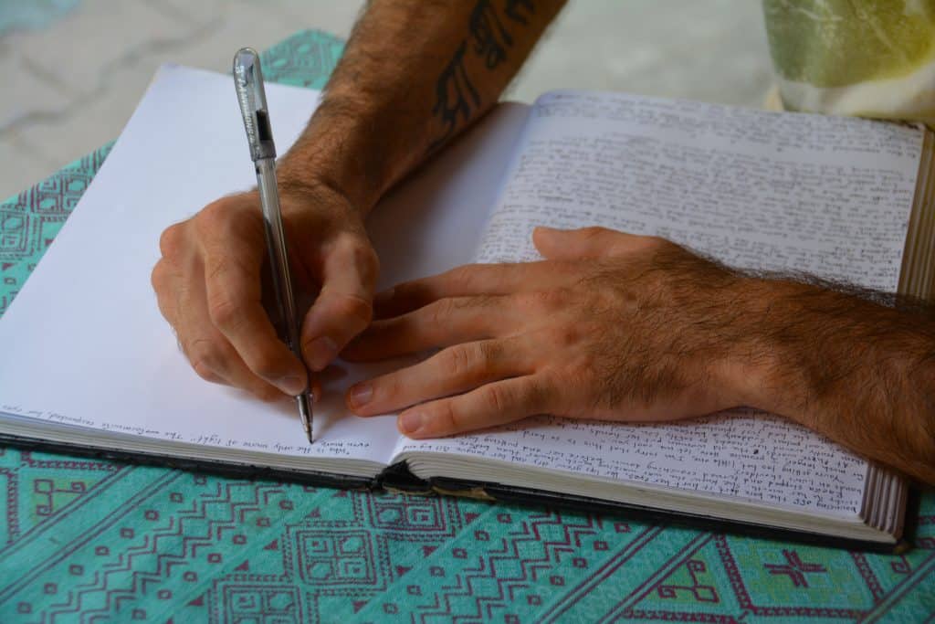 Why Most Memoirs Don’t Work post shows a man writing in an A4 book with over half of it written in biro already. The man's hand is just starting on a new blank page.